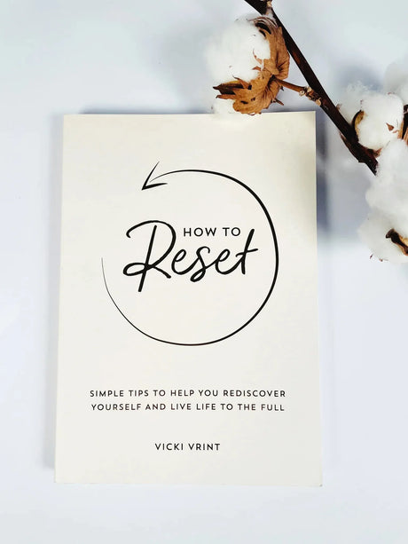 Minimalist book titled How to Reset with a decorative cotton sprig on a clean white background.